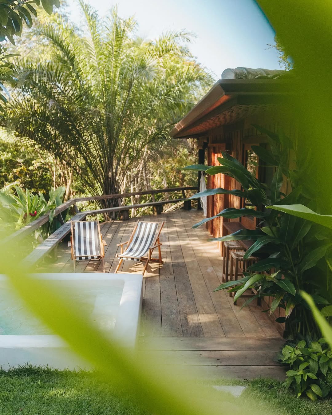 Deck de madeira com espreguicadeiras listradas ao lado da piscina
